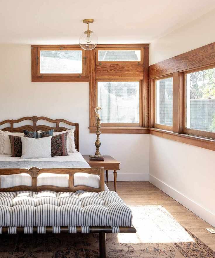 Bedroom with traditional wooden window frames and dark wooden bed frame