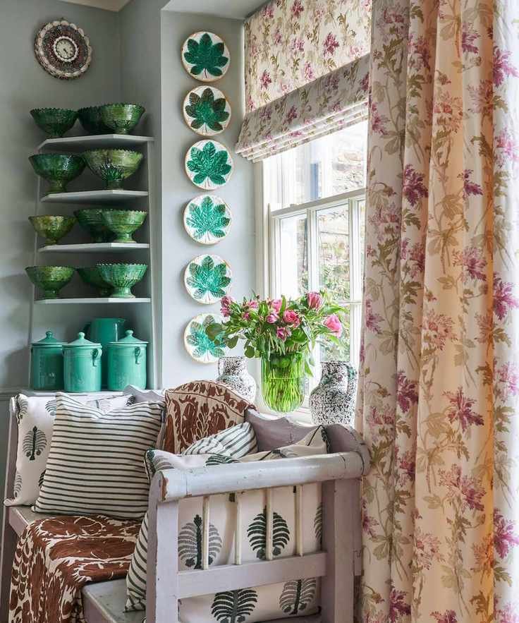 A collection of decorative plates displayed in a window recess and Moroccan green glazed pottery on shelves