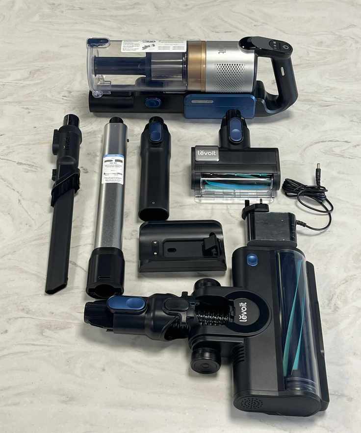 Levoit LVAC-300 cordless vacuum cleaner and all parts and attachments laid out on marble surface in testing center.
