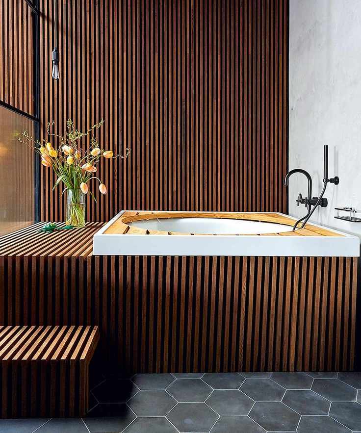 wood-paneled bathroom with tub and black tiles