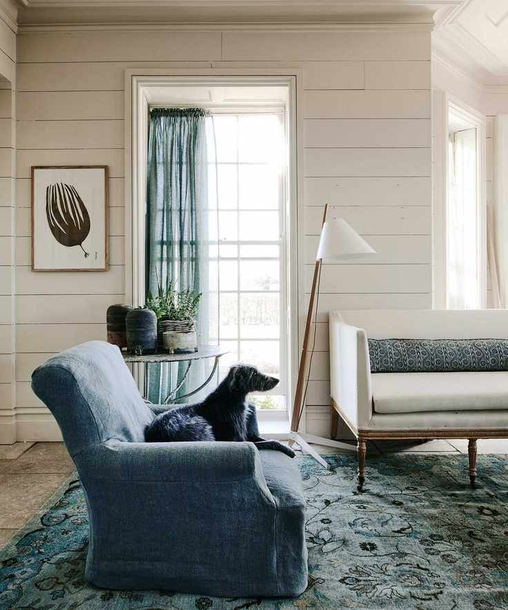 living room with blue linen armchair, curtains, and antique sofa