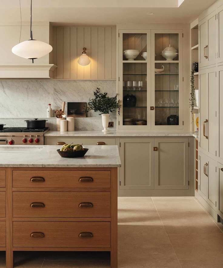 a warm neutral two tone kitchen with a glass fronted cabinet and a warm wooden island