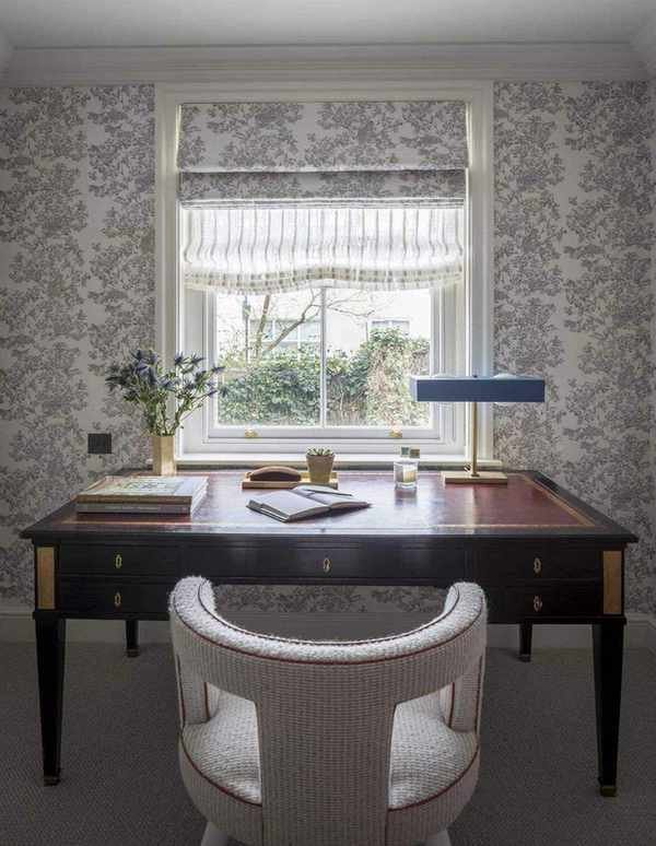 desk in front of a window with roman blinds, lamp and stationery