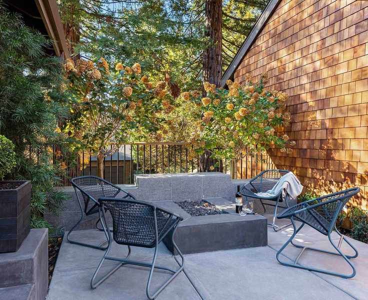Sleek gray patio furniture in a small concrete area with a brick wall.