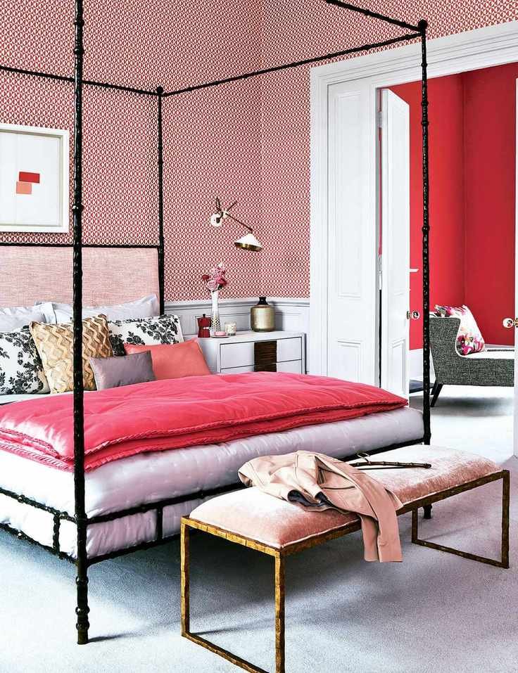Pink bedroom with patterned wallpaper and black four poster bed