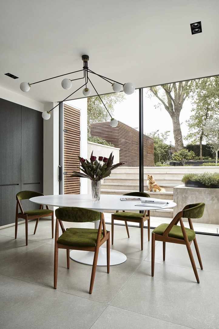dining room with white table and green chairs, statement pendant light and sliding doors