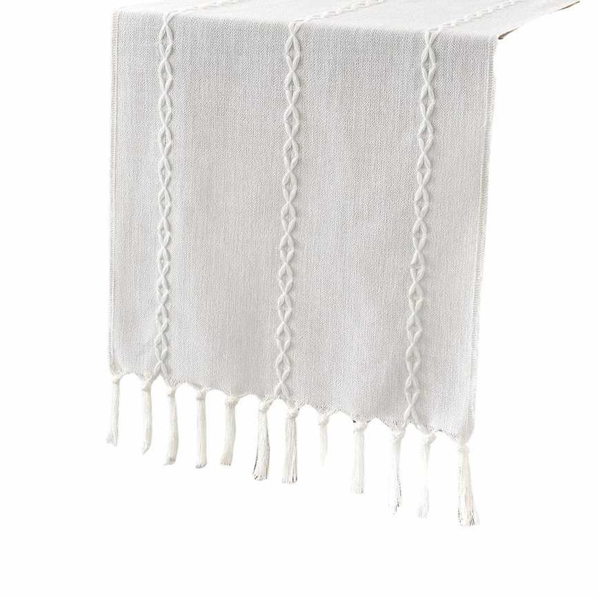 A white table runner with tassels and an embroidered pattern on it