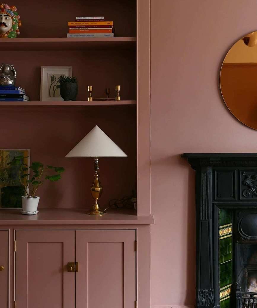 Pink shelves in living room with fireplace, lamp and objects