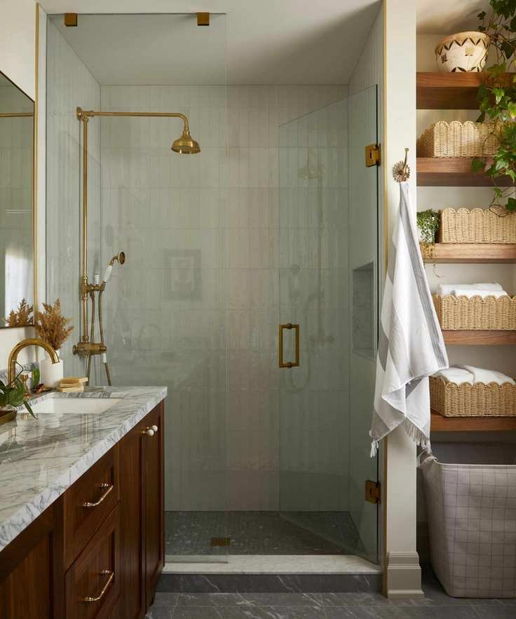 a warm neutral ensuite bathroom with a dark wooden floating vanity with marble top, shower enclosure, and wooden floating shelves