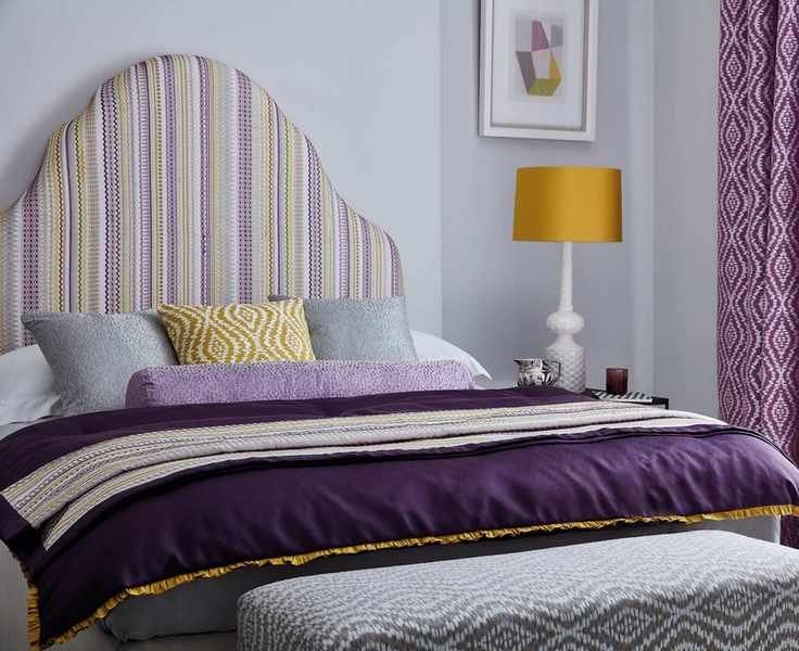 Lilac painted bedroom with large bedside table and purple curtains