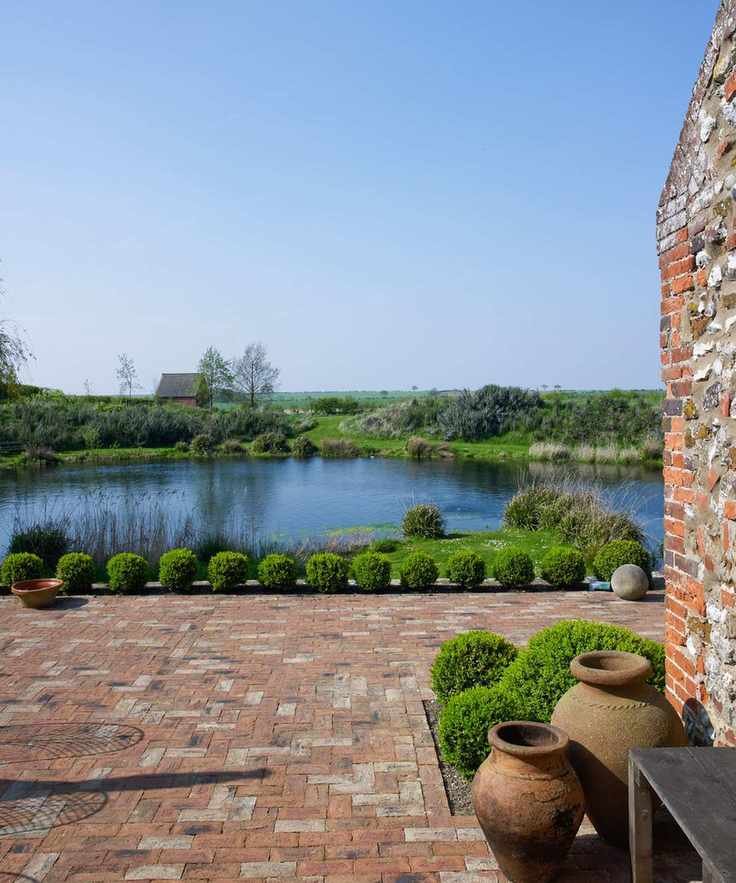 A brick paved courtyard with small round hedges