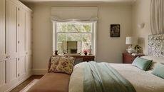 Traditional bedroom with cream walls, built in cabinets and a pattern headboard