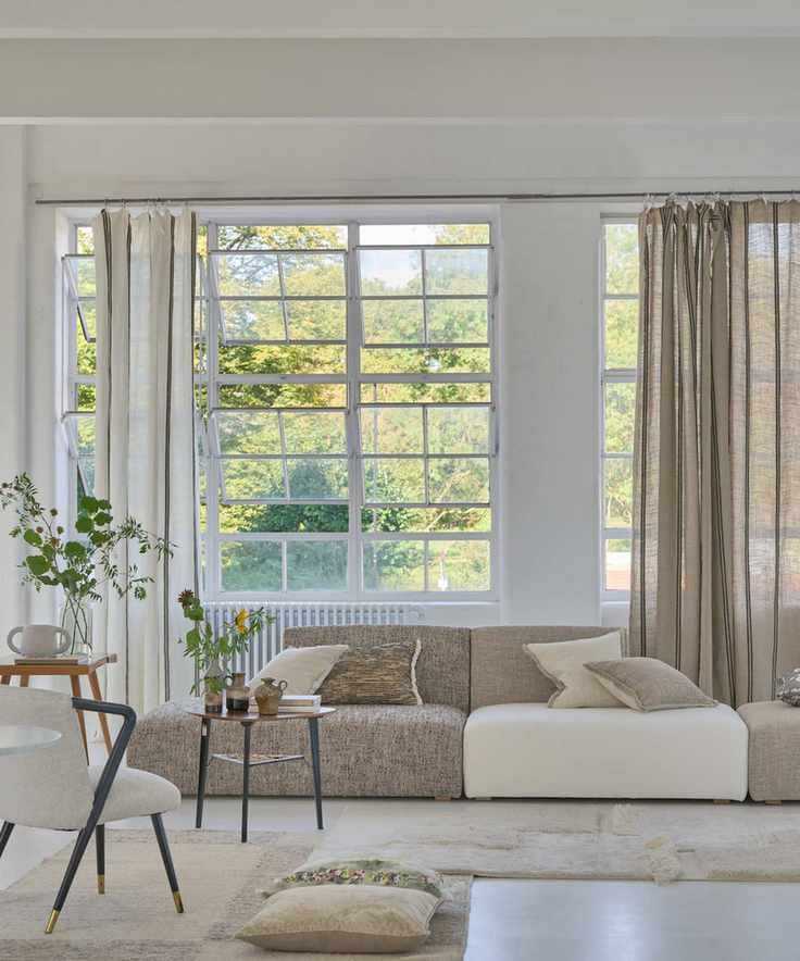 timeless interior design styles, modern living room with white walls, layered rugs, retro chair, side table, low slung couch, linen curtains