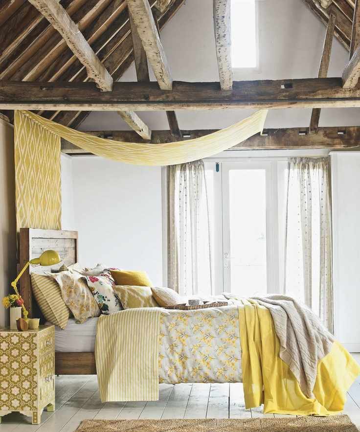 Bedroom, oak beams timber frame, rustic bed, assorted cushions and pillows, floral quilt. French windows, diamond pattern canopy