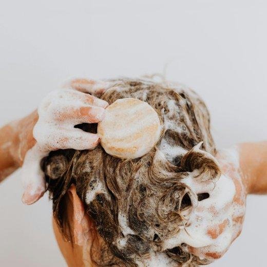 Image of model applying shampoo to their hair