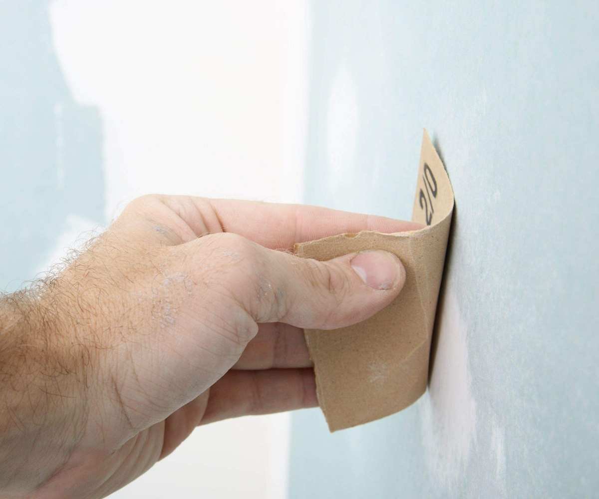 Someone removing paint from wall