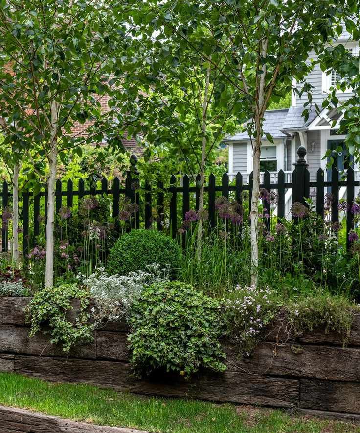 A picket fence accompanied by raised antique sleeper flower beds.