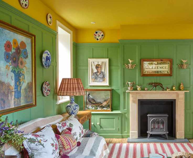 Colorful living room with yellow painted ceiling, green painted paneled walls, eclectic mix of framed artwork and pictures, decorative plates on the wall