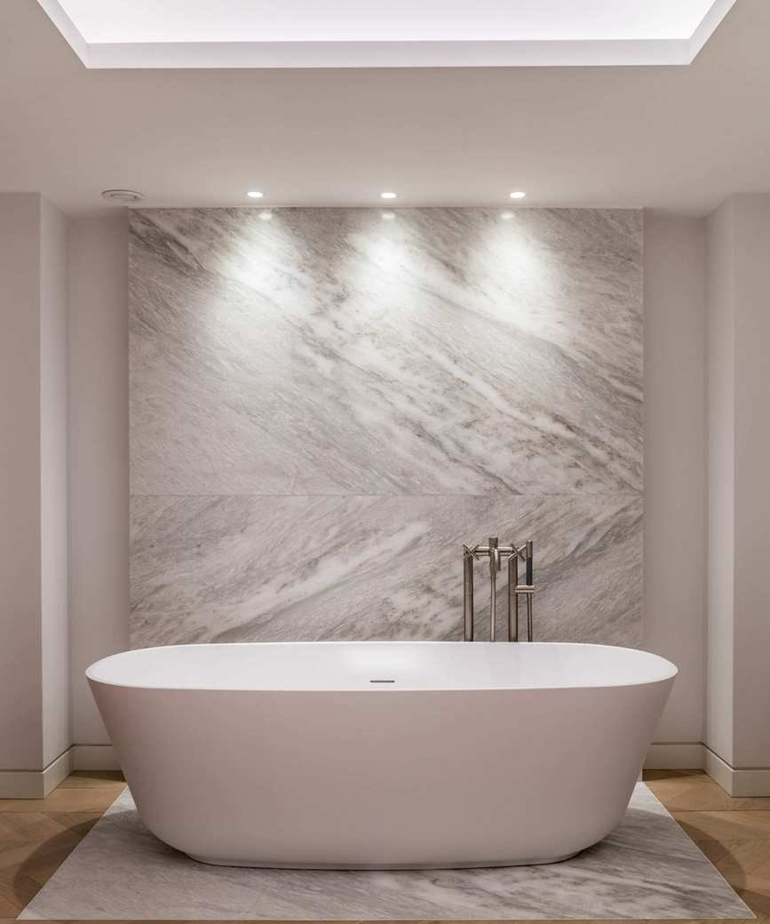 An example of LED bathroom lighting ideas showing a large white bath below three spotlights