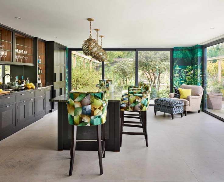 Interior of a pool house showcasing a kitchen with geometric stools and curtains.