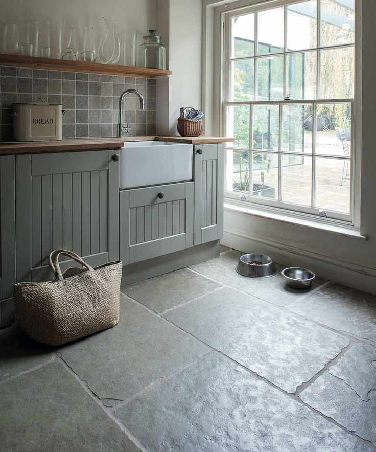 A dark mudroom with two dog bowls, a sink area and a large window