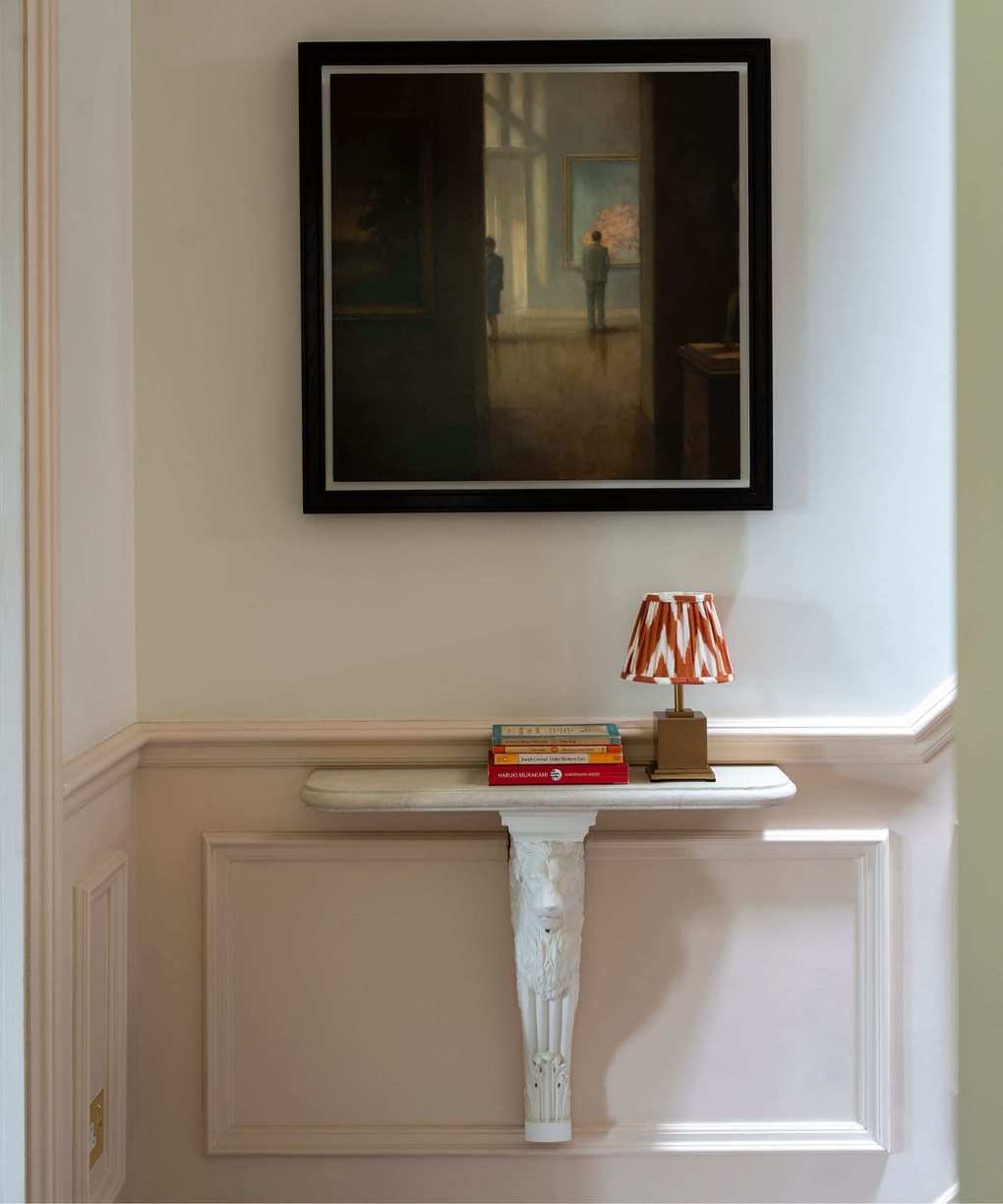 An entryway with pink panelled baseboards and a white table.