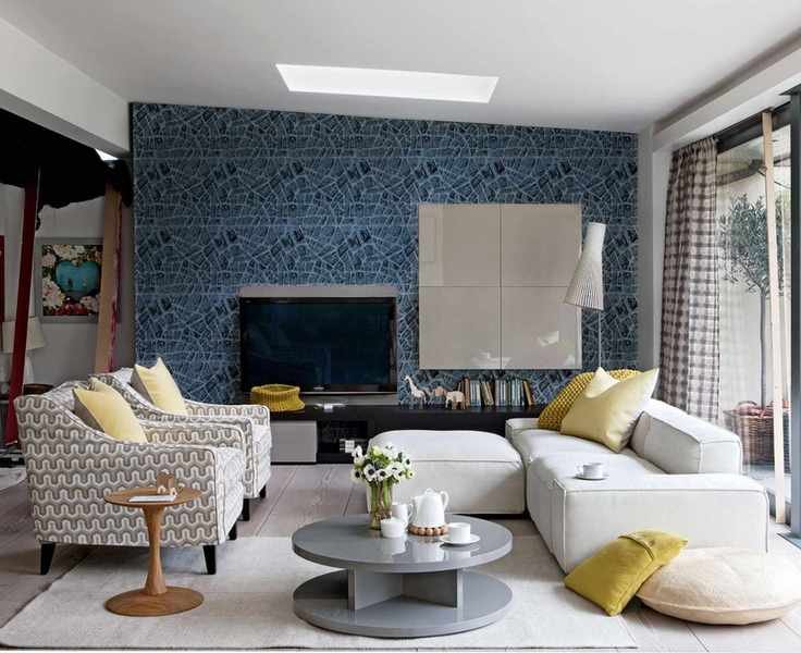 Open-plan family room with large cream sofa and two patterned lounge chairs, accessorized with yellow cushions and light wooden flooring