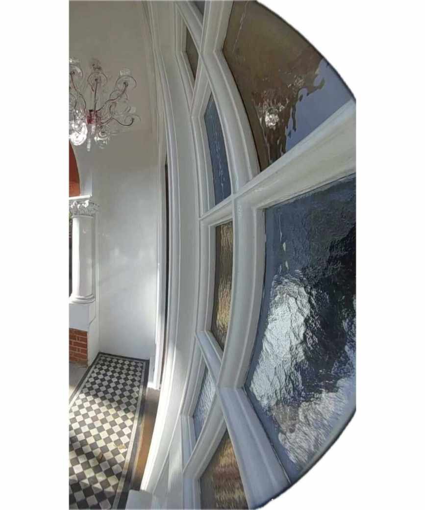 The view of my black and white tiled porch from my Ring Battery Doorbell Plus. To the right are stained glass panels, and above is an acrylic light with pink wiring.