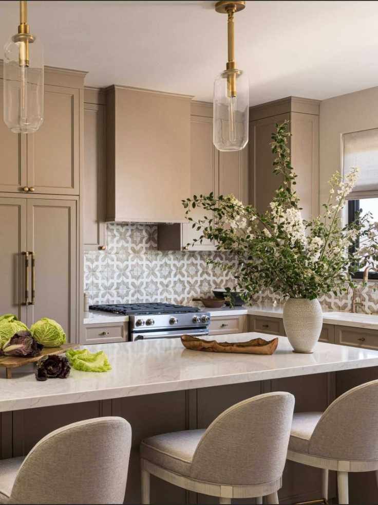 A warm neutral small kitchen with an island and cabinets that go to the ceiling