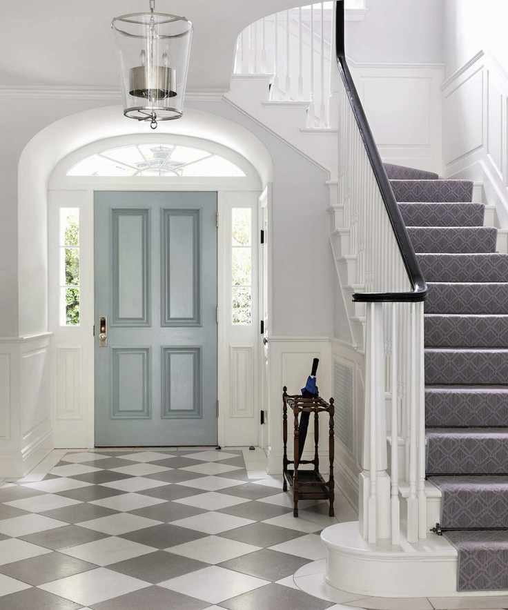A hallway with gray and white checkered floor tiles and front door