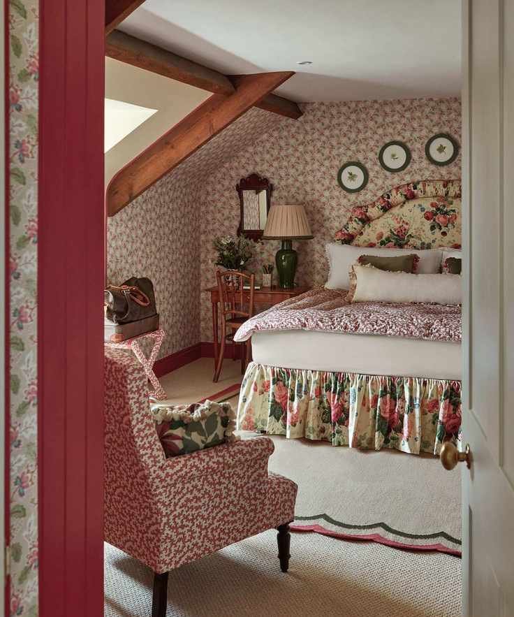 Cottage bedroom with wallpaper and a floral headboard and bed valance