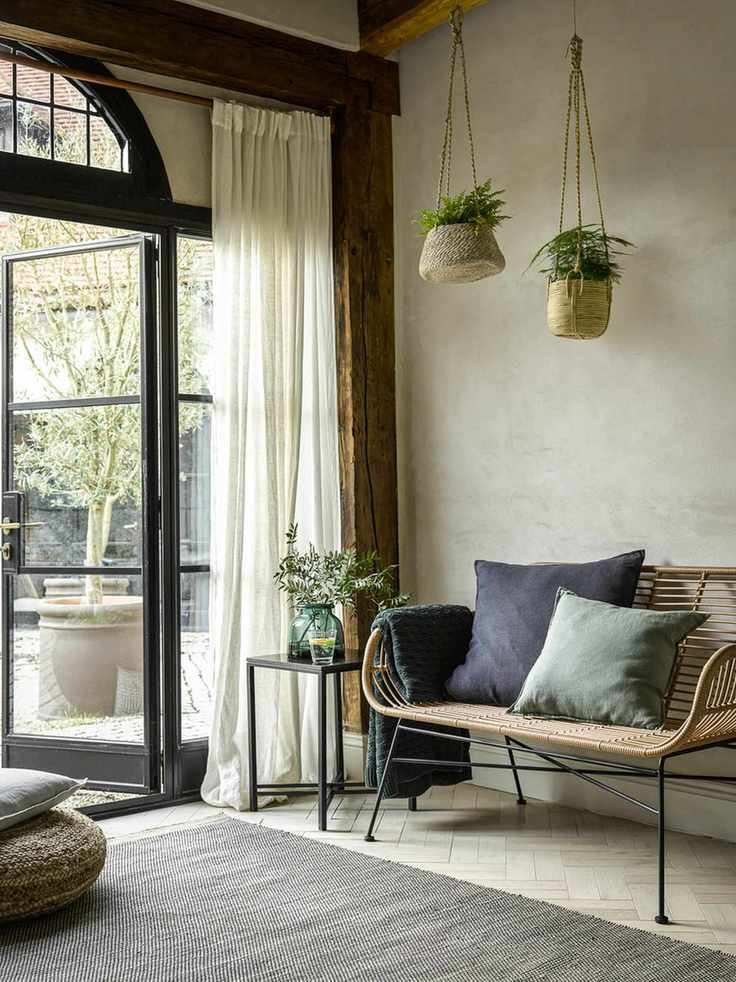 A foyer with large windows, wicker hanging baskets and wicker furniture