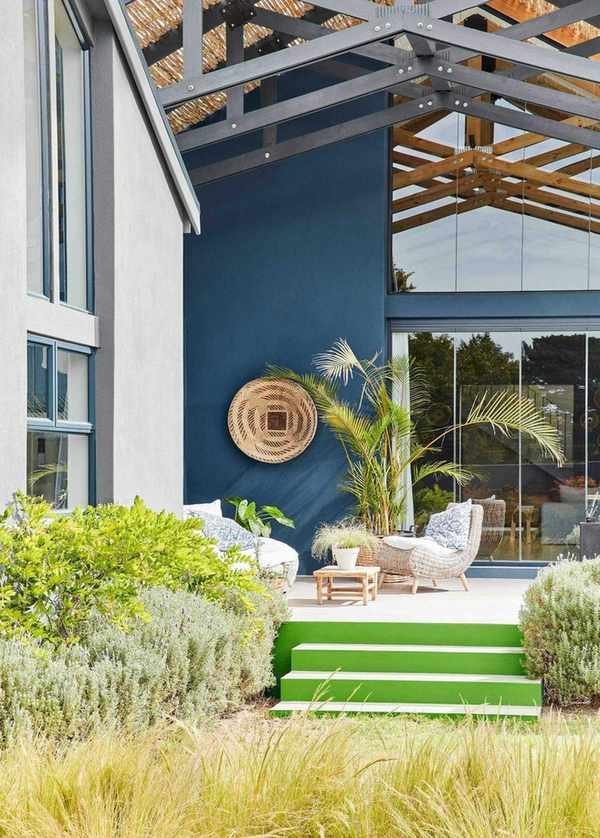 A large house with a blue outdoor wall and bright green steps leading down to a grassy garden
