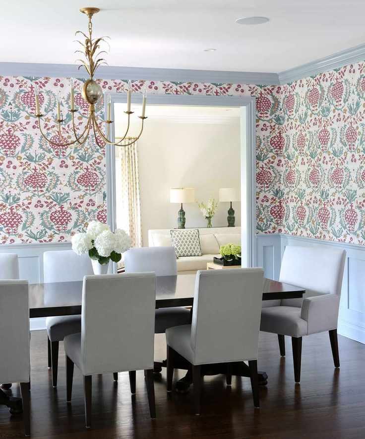Bright dining room featuring floral wallpaper, light blue wood paneling, and a dark wood dining table