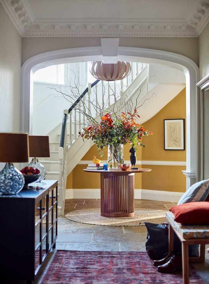 Modern country hallway with yellow paint, and a central circular table.