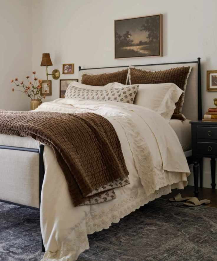 magnolia bedroom neutral walls with linen an black iron metal bedframe, white sheets, floral black print pillow and quilt
