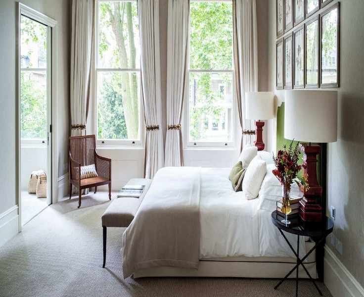 A bright and white carpeted minimalist bedroom with a large bed and stylish decor.