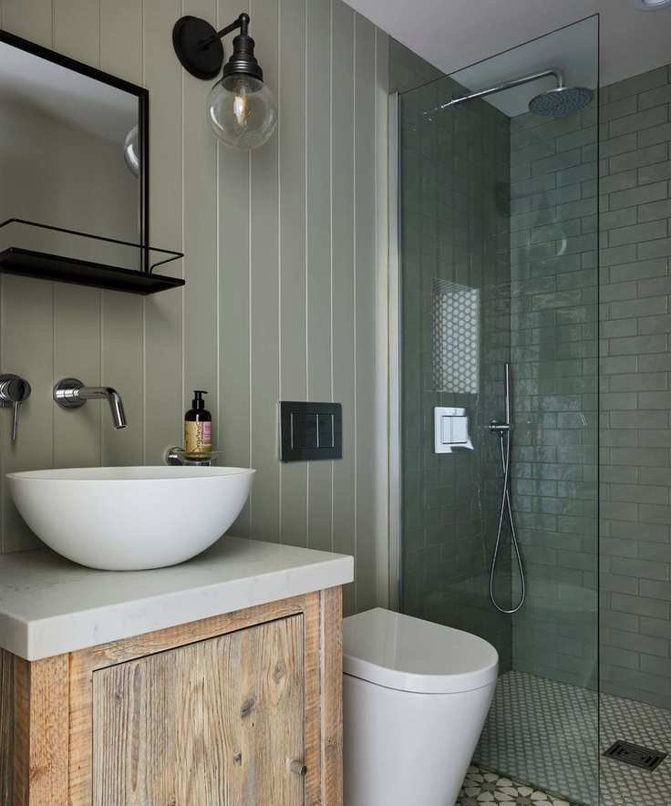 A small green bathroom with subway tiles and paneling.