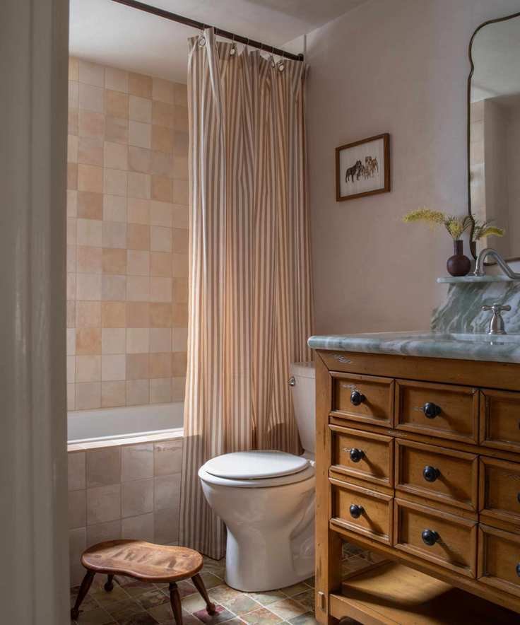 bathroom with neutral walls, earth shower tiles, striped shower curtain and wooden vanity unit