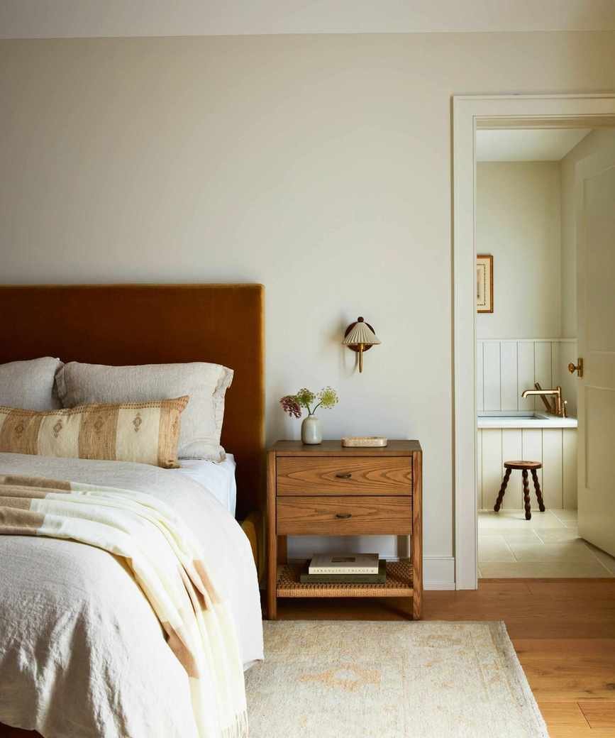 bedroom with cream walls and velvet headboard in warm brown tones