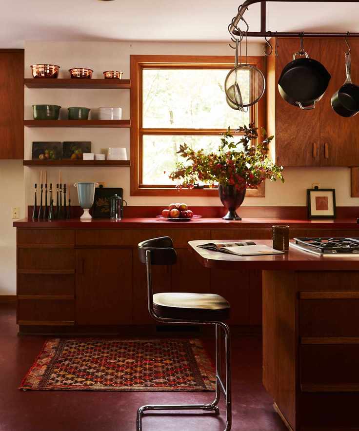 Midcentury kitchen with wood cabinets and wood island, midcentury stools and china and pottery on shelves