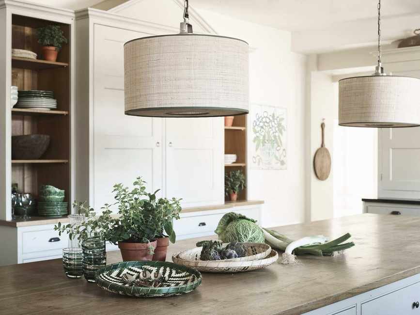 raffia drum pendant shade above kitchen island with wooden countertop, decorated with food and plates