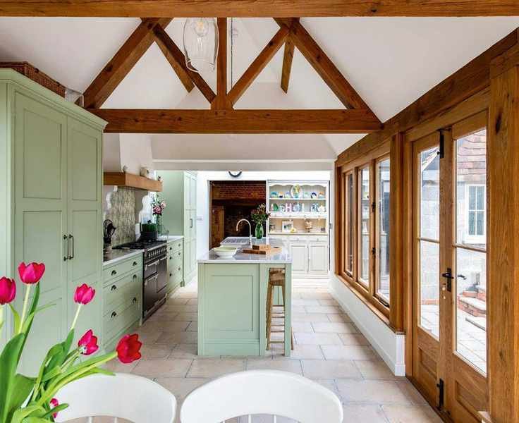 green kitchen in an oak frame extension with patio doors