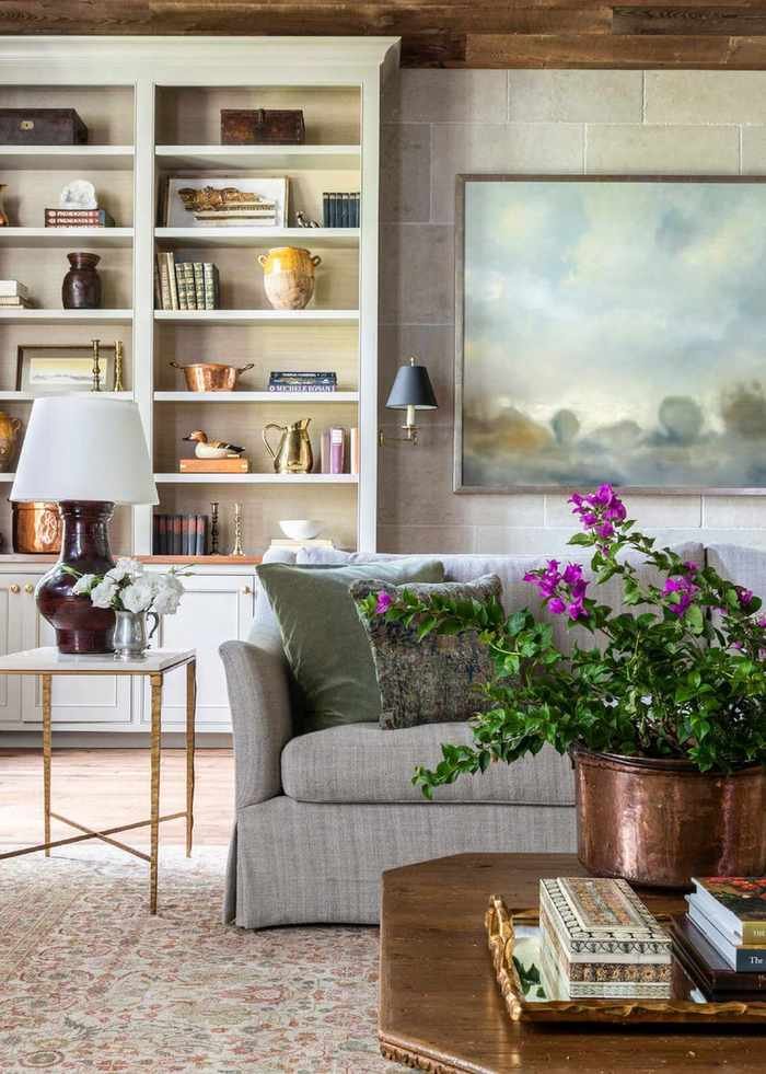Farmhouse decor ideas, cozy living room with patterned rug, gray sofa, wooden coffee table, white shelving, large artwork