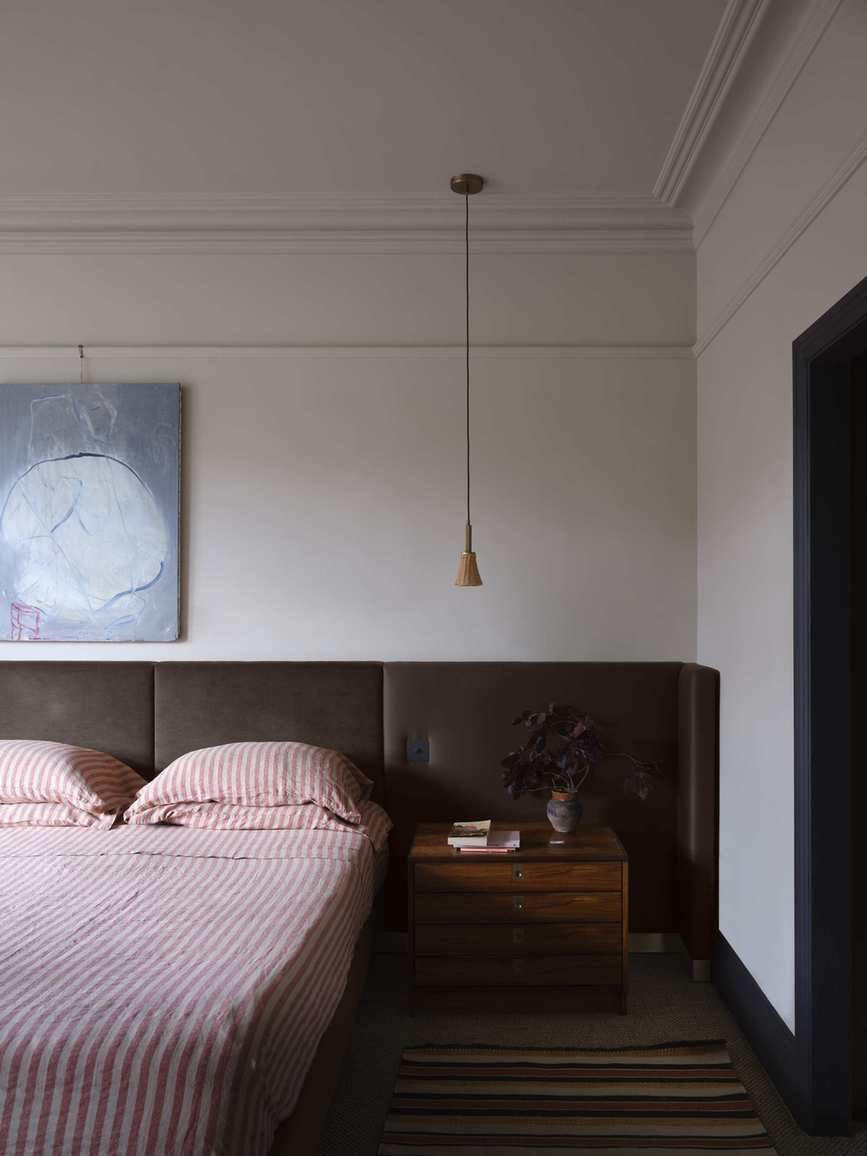A mid-century style bedroom with a large brown headboard and red and white striped bedding