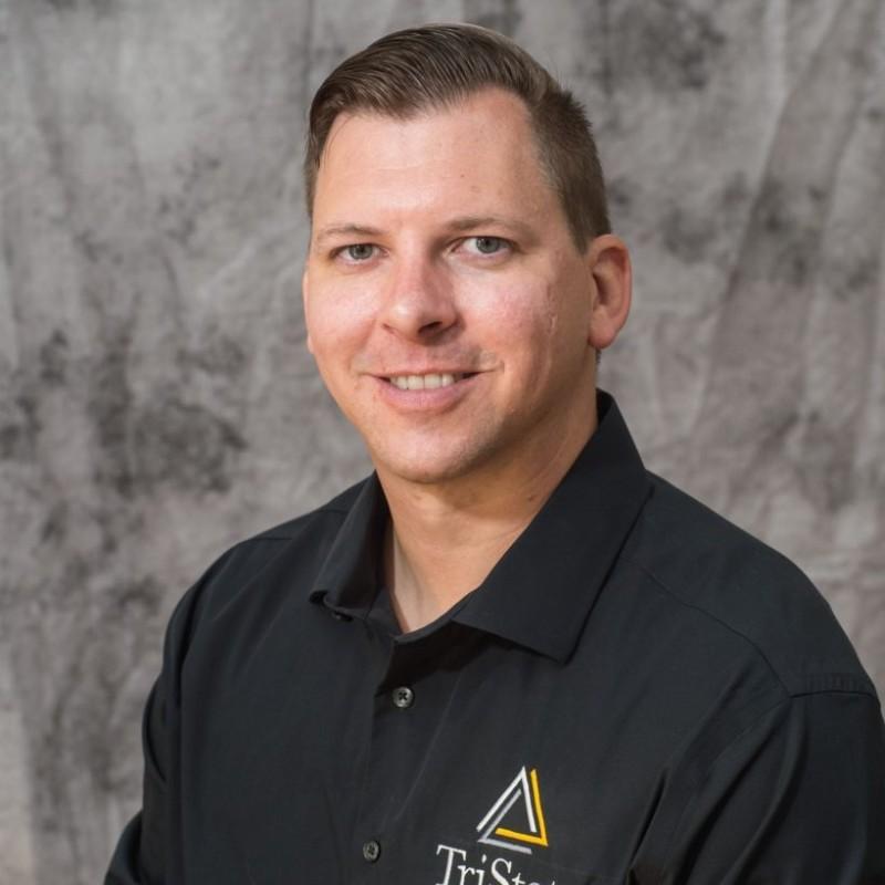 Bert is a white man in a black polo shirt, pictured in a professional headshot on a gray background