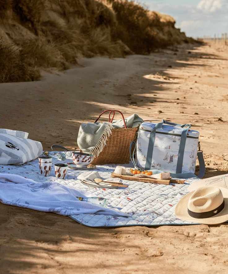 picnic blanket with beach bag and cool bag on a sandy beach