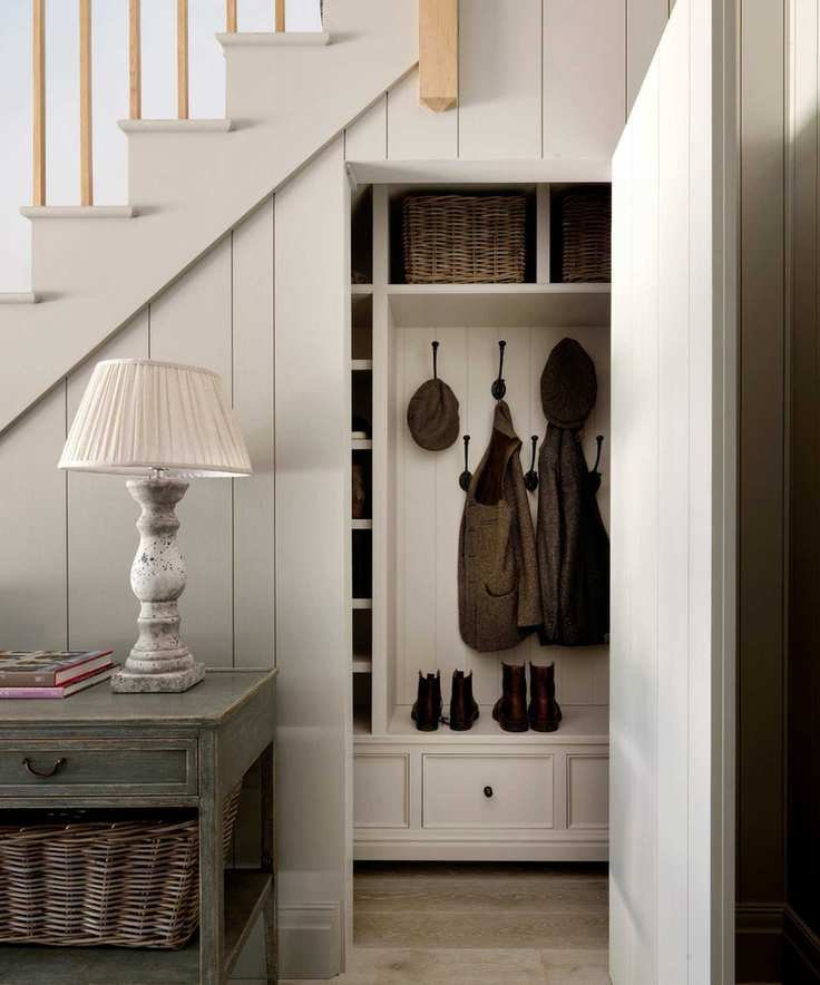 white panelled painted staircase with a boot room hidden underneath behind a concealed door that opens up to boot and coat storage