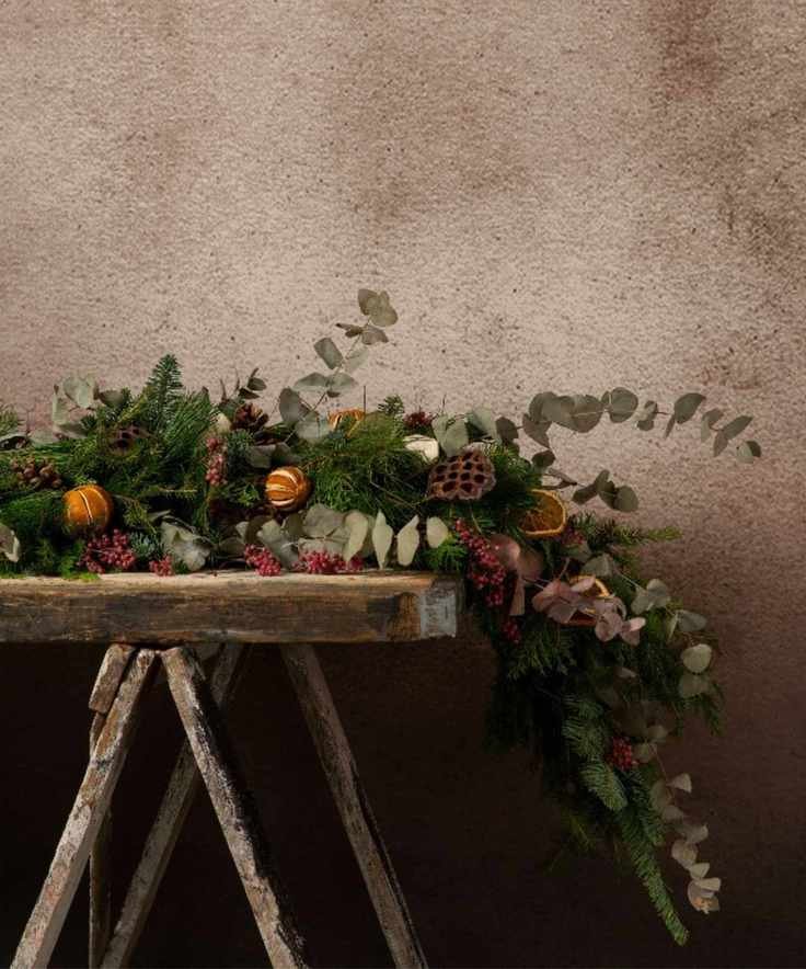 A rustic side table with a large real pine garland decorated with dried fruits