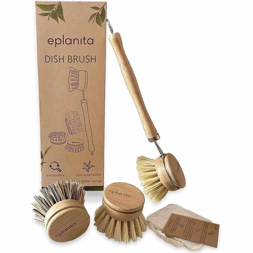 A wooden handled bamboo dish brush leaning against a brown cardboard packaging box with two spare wooden heads